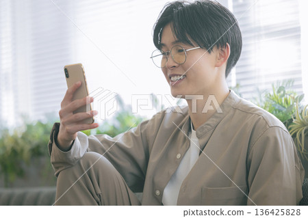A man looking at a smartphone in the room A man looking at a smartphone in the room 136425828