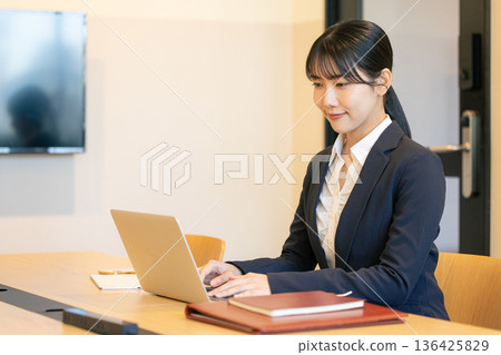 Smiling young woman using a laptop Smiling young woman using a laptop 136425829