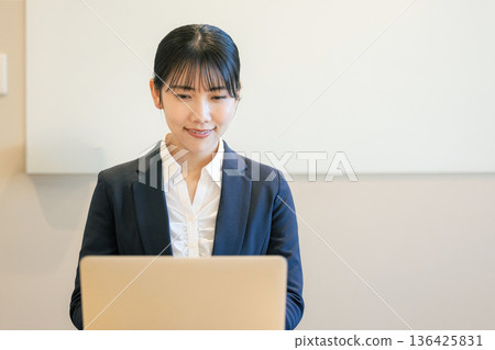 Smiling young woman using a laptop Smiling young woman using a laptop 136425831