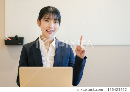 一位微笑的年輕女子正在使用筆記型電腦 136425832