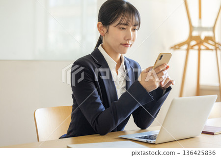 操作智慧型手機的年輕女商人 136425836