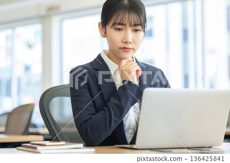 一位身穿西裝的女士看著筆記型電腦，神情憂慮。 136425841