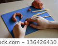 Kids clay sculpting master class flat lay step 2 shaping basic forms with hands creative educational activity fine motor skills development handmade craft process 136426430