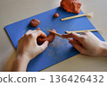 Kids sculpting clay flat lay step 4 using wooden tools to refine shape and texture creative handmade craft educational activity fine motor skills concept 136426432