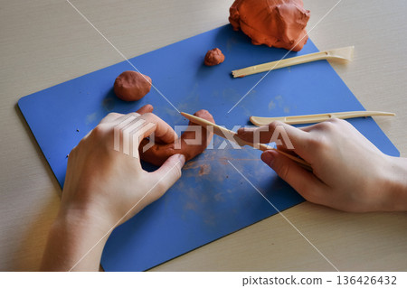 Kids sculpting clay flat lay step 4 using wooden tools to refine shape and texture creative handmade craft educational activity fine motor skills concept Kids sculpting clay flat lay step 4 using wooden tools to refine shape and texture creative handmade craft educational activity fine motor skills concept 136426432