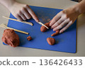 Children clay sculpting master class flat lay step 5 connecting separate parts and smoothing surface creative educational handmade craft process 136426433