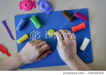 Kids plasticine sweets candy and lollipops modeling flat lay step 5 shaping round elements for handmade candy creative play diy craft fine motor skills development educational concept 136426439