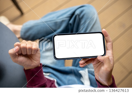 A man's hand holding blank screen smartphone making a fist in excited while sitting at table in cafe A man's hand holding blank screen smartphone making a fist in excited while sitting at table in cafe 136427613