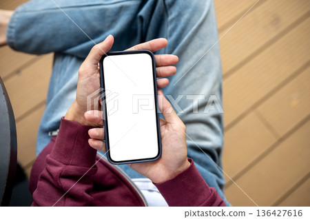 A man's hands holding blank screen smartphone while sitting at table in the cafe or coffee shop. 136427616