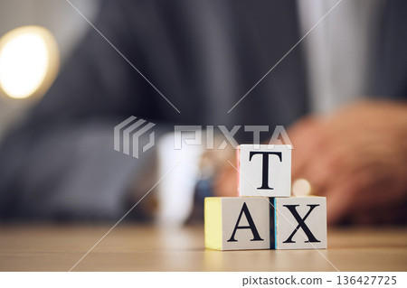Business person, hands and blocks for tax, financial advisor or accounting on office desk. Letter or word of finance accountant, lawyer or real estate in revenue, property investment or loan income 136427725