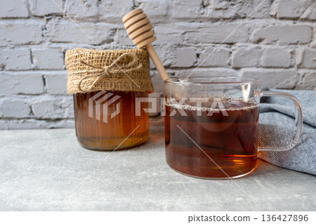 Honey jar with honeycomb, cap of tee and wood spoon stay on the table. Food concept. Honey jar with honeycomb, cap of tee and wood spoon stay on the table. Food concept. 136427896