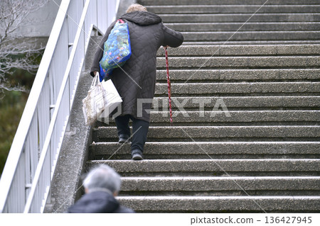 Yokohama cityscape in Japan. Even climbing the stairs is a struggle... steps and unevenness... aging society. Elderly woman with a walking stick = Yokohama city Yokohama cityscape in Japan. Even climbing the stairs is a struggle... steps and unevenness... aging society. Elderly woman with a walking stick = Yokohama city 136427945