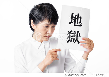 一位老婦人手裡拿著一張寫著「地獄」二字的紙，悲傷地低著頭。 136427959