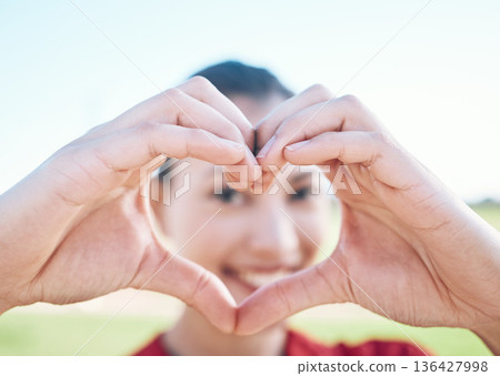 Heart shape, closeup and hands of woman with a care, sweet and cute gesture outdoor on a field. Happy, smile and zoom of a young female person with a love sign or emoji in a outside park or garden. 136427998