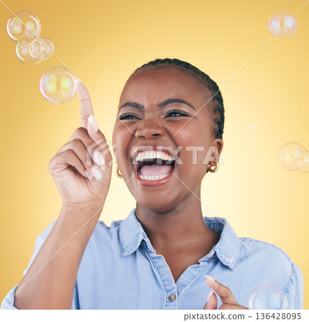 Excited, laugh and black woman on yellow background with bubbles for happiness, joy and have fun. Happy, smile and isolated African person in studio pop soap bubble for playful magic and color Excited, laugh and black woman on yellow background with bubbles for happiness, joy and have fun. Happy, smile and isolated African person in studio pop soap bubble for playful magic and color 136428095