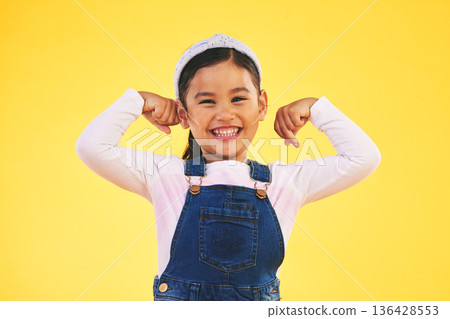Smile, portrait and girl child with arm flex in studio for confidence, strong and power on yellow background. Happy, face and excited kid with bicep strength, pose or empower, positive or growth sign 136428553
