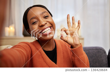 Selfie, black woman and ok hand sign at home with a smile for success, motivation and perfect. Portrait, happy and African female person in a living room with a like, yes and emoji gesture at house 136428684