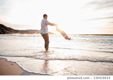 Swing, beach and father with playing child holding hands in nature for freedom or bonding at sunset. Ocean, travel and parent with girl at sea for spinning fun, games or celebration adventure in Bali Swing, beach and father with playing child holding hands in nature for freedom or bonding at sunset. Ocean, travel and parent with girl at sea for spinning fun, games or celebration adventure in Bali 136428834