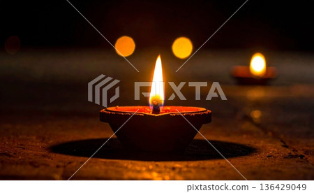 A glowing wax candle flame flickers with a warm light, burning brightly against the dark black night to create a peaceful atmosphere of romance and celebration A glowing wax candle flame flickers with a warm light, burning brightly against the dark black night to create a peaceful atmosphere of romance and celebration 136429049