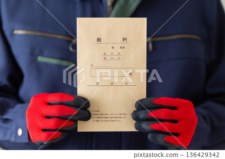 Middle-aged male businessman in work clothes holding a pay packet Middle-aged male businessman in work clothes holding a pay packet 136429342