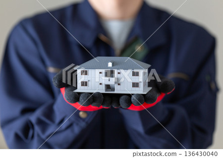 A middle-aged male businessman in work clothes holding an apartment model 136430040