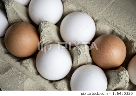 White and brown fresh eggs. Nature background. Chicken egg in carton box for cooking healthy food. Bio organic eggs on the farm. 136430320
