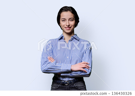 Portrait of smiling young confident girl looking at camera on white background Portrait of smiling young confident girl looking at camera on white background 136430326