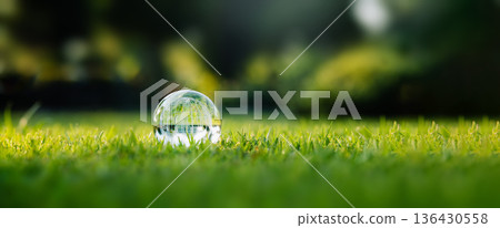 Crystal glass globe resting on green grass, concept for ecology and environment. Crystal glass globe resting on green grass, concept for ecology and environment. 136430558