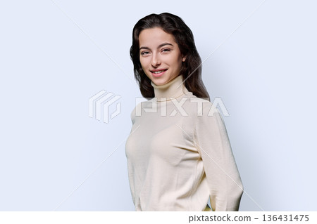 Portrait of beautiful smiling teenage woman against white studio background Portrait of beautiful smiling teenage woman against white studio background 136431475