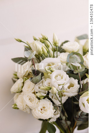 White carnation wed bouquet with wrapped stems leaning against white wall in sunlight White carnation wed bouquet with wrapped stems leaning against white wall in sunlight 136431478