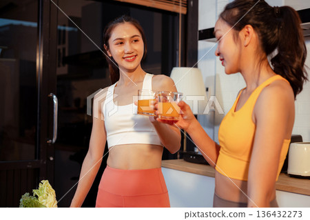 Two sporty women drinking smoothie and eating fresh vegetables. Two sporty women drinking smoothie and eating fresh vegetables. 136432273