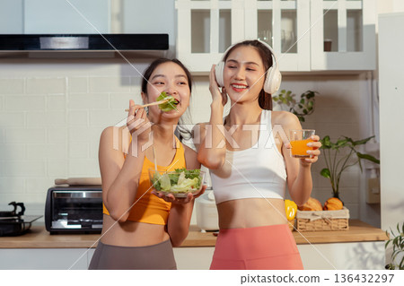 Two sporty women drinking green smoothie and eating fresh vegetables. Two sporty women drinking green smoothie and eating fresh vegetables. 136432297