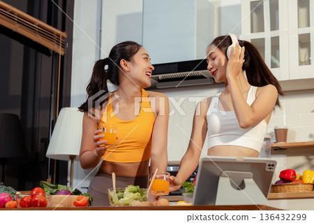 Two sporty women drinking green smoothie and eating fresh vegetables. 136432299
