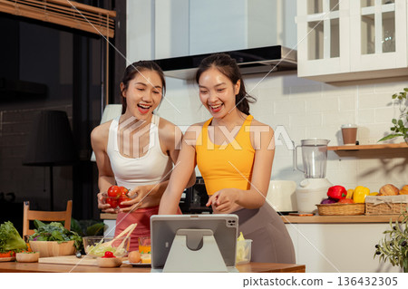 Two sporty women drinking green smoothie and eating fresh vegetables. Two sporty women drinking green smoothie and eating fresh vegetables. 136432305