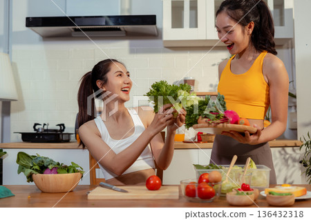 Two sporty women drinking green smoothie and eating fresh vegetables. Two sporty women drinking green smoothie and eating fresh vegetables. 136432318