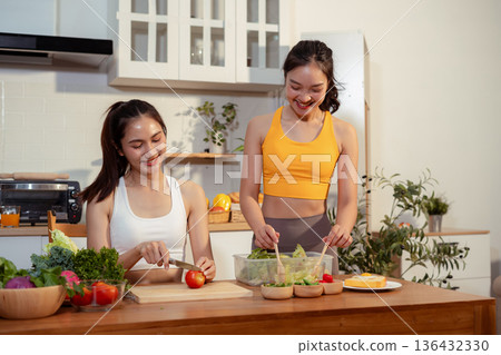 Two sporty women drinking green smoothie and eating fresh vegetables. Two sporty women drinking green smoothie and eating fresh vegetables. 136432330