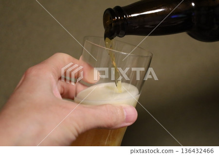 Close-up of the moment beer is poured into a glass: a golden, foamy drink Close-up of the moment beer is poured into a glass: a golden, foamy drink 136432466
