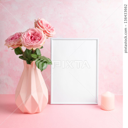 Romantic composition Pink vase with roses, blank frame, and candle on pastel pink background Mockup 136433662