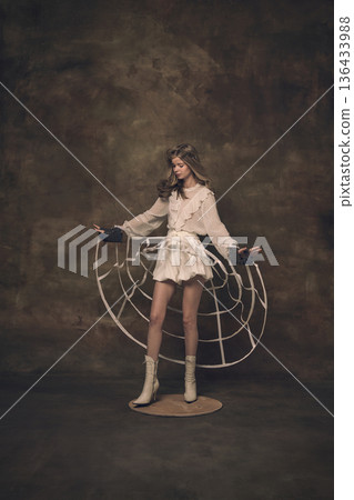 Female model adjusting abstract hoop structure around waist in studio 136433988