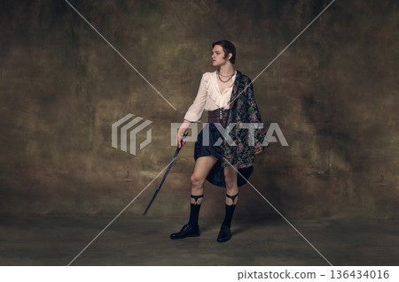 Androgynous warrior holding sword in vintage studio setting. Androgynous warrior holding sword in vintage studio setting. 136434016