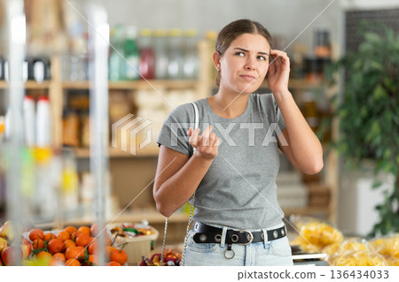 Thoughtful woman in a supermarket Thoughtful woman in a supermarket 136434033