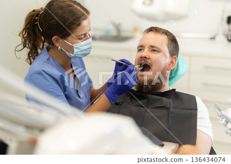 man sits in a chair at an appointment at a dental clinic man sits in a chair at an appointment at a dental clinic 136434074