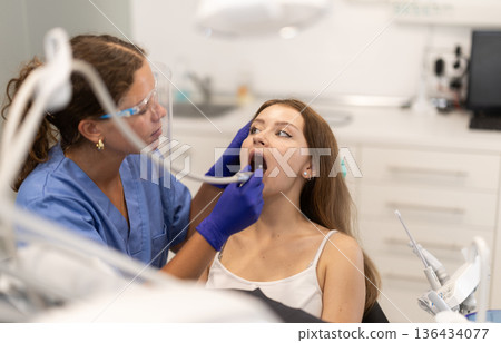 Woman dentist drilling and treating teeth of woman in clinic Woman dentist drilling and treating teeth of woman in clinic 136434077