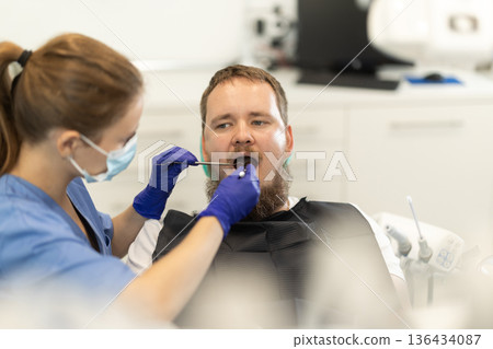 man sits in a chair at an appointment at a dental clinic 136434087