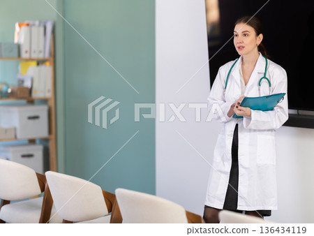 Young woman doctor gives lecture with folder Young woman doctor gives lecture with folder 136434119