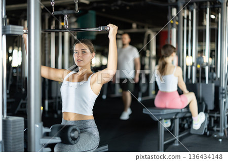 Young woman training her arms on machine Young woman training her arms on machine 136434148