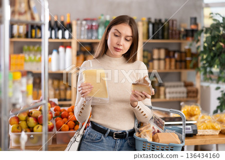 Girl looking at cheese in store 136434160