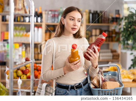 Young woman choosing juices in grocery store Young woman choosing juices in grocery store 136434165