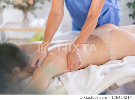 Woman enjoys light therapeutic massage Woman enjoys light therapeutic massage 136434214