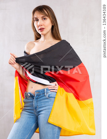 Attractive female football fan holding Germany flag 136434389